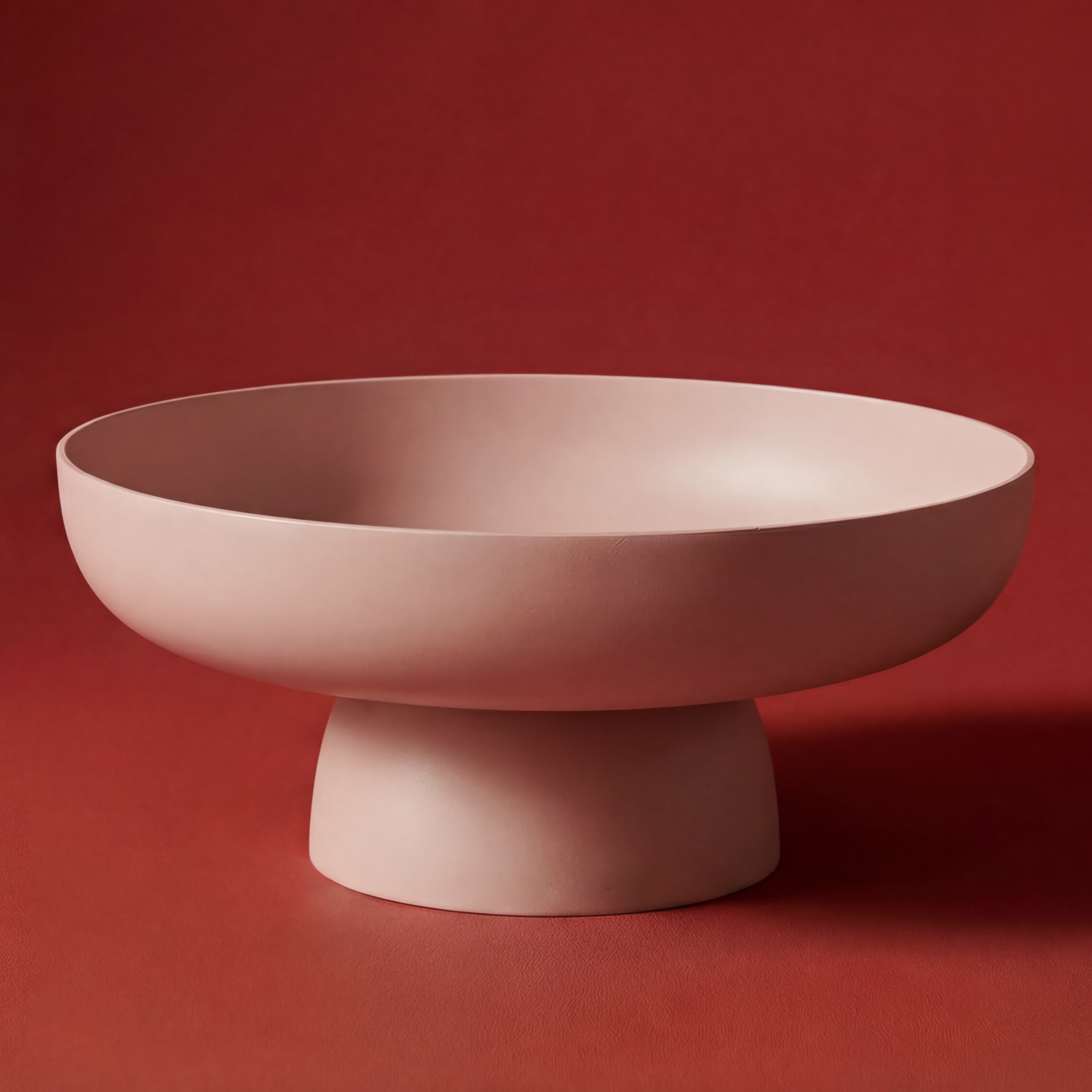 Runda Bowl in Blush by Maxim Vogel, a warm matte serving bowl photographed against a deep red background.